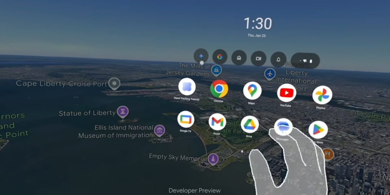 من موقع فون إسلام: تعرض واجهة الواقع الافتراضي، مثل واجهة نظارة أبل فيجنو أيقونات التطبيقات فوق منظر جوي لمنطقة تمثال الحرية، مع يد شفافة تختار أحد التطبيقات والوقت يظهر على أنه 1:30.