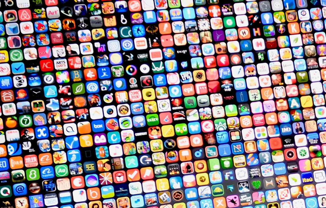 من موقع فون إسلام: مئات من أيقونات التطبيقات الملونة مرتبة في شبكة كثيفة، تمثل مجموعة متنوعة من تطبيقات الهاتف المحمول و رسوم التطبيقات المصغرة على شاشة آبل.