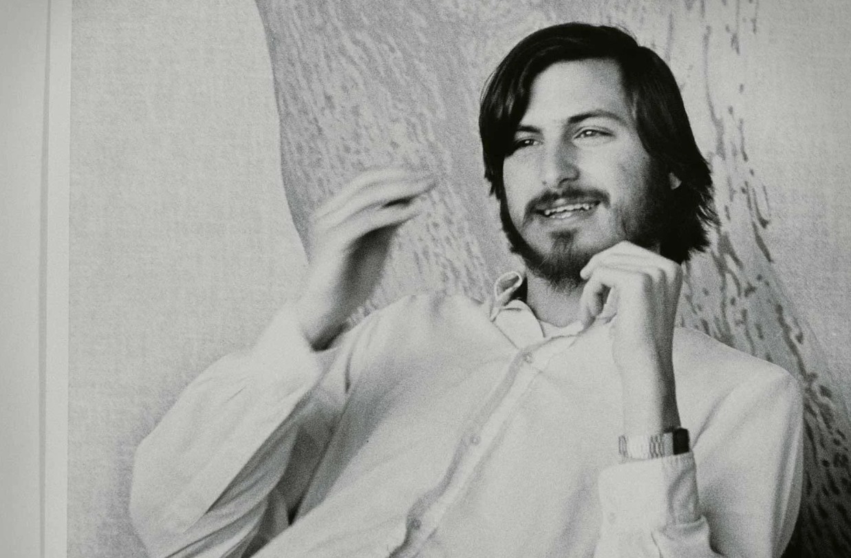 من موقع فون إسلام: يجلس شاب بشعر يصل شعره إلى كتفيه ولحية مسترخياً مرتدياً قميصاً فاتح اللون وساعة يد، ويشير بيديه ويبتسم - وهو ما يذكرنا بستيف جوبز في أوائل ستوديو صغير. الخلفية خارج نطاق التركيز.