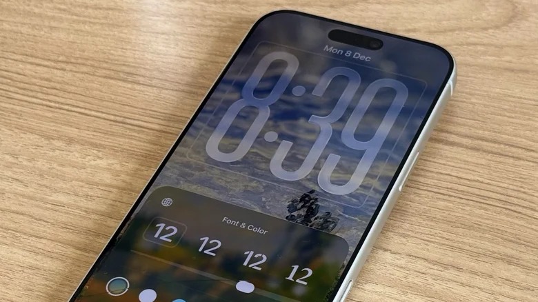 Von PhoneIslam: Ein Smartphone auf einer Holzoberfläche zeigt das Menü zur Anpassung des Sperrbildschirms von iOS 26.3 und hebt das iOS-Update mit neuen Schriftart- und Farboptionen hervor.