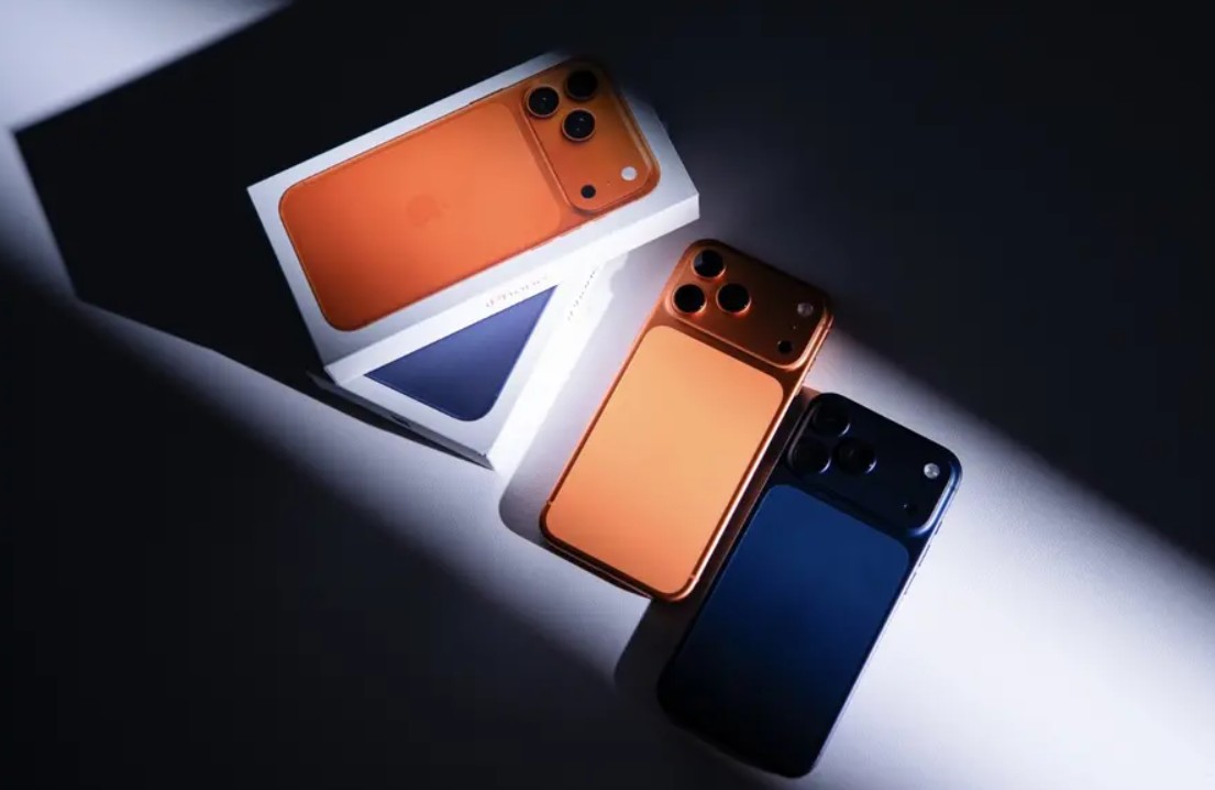 من موقع فون إسلام: هاتفان ذكيان، أحدهما برتقالي والآخر أزرق، يجلسان بجانب صندوق هاتف برتقالي، مضاءان جزئياً بشعاع ضوئي مائل، ربما في انتظار شحنهما التالي مجاناً من "ماسوشيتس" أو "ضوضاء".