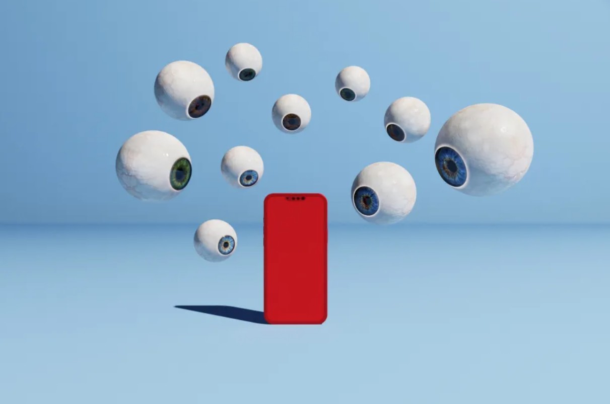 Van PhoneIslam: Een rode smartphone staat rechtop op een vlak blauw oppervlak, omringd door verschillende zwevende oogbollen in verschillende kleuren op een blauwe achtergrond, wat een digitale alertheid oproept die doet denken aan nieuwsberichten uit Egypte of Saoedi-Arabië.