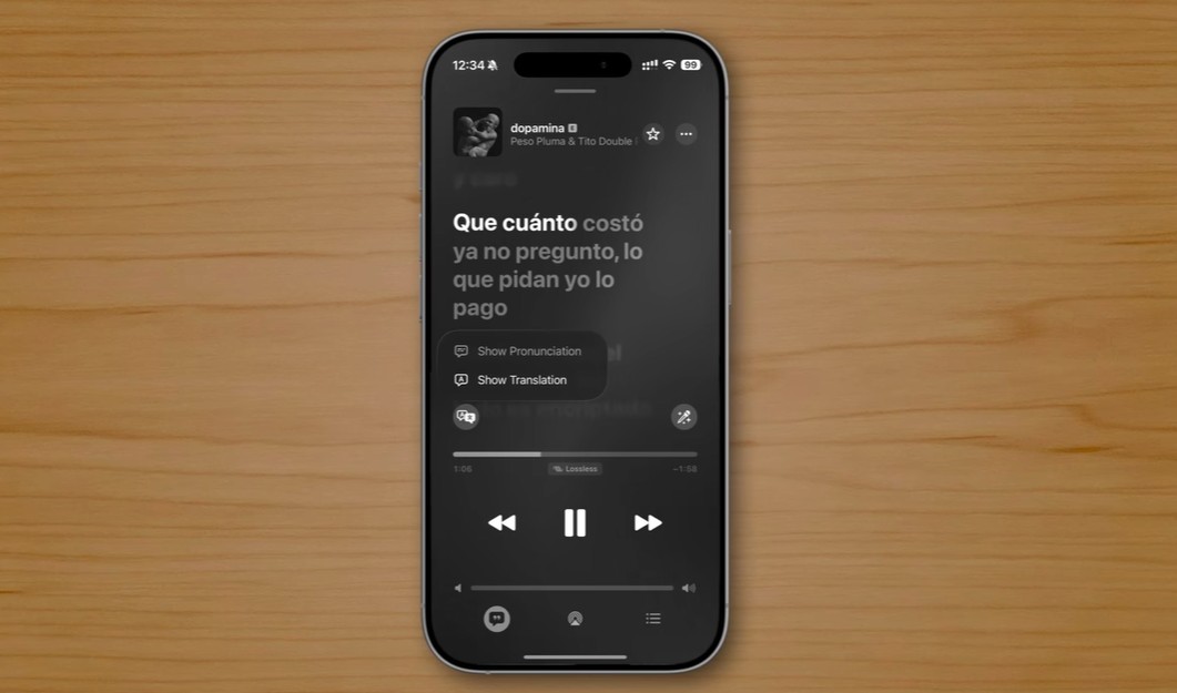 من موقع فون إسلام: يعرض الهاتف الذكي الذي يعمل بنظام iOS 26 على سطح خشبي مشغل موسيقى بكلمات باللغة الإسبانية لأغنية "دسبامينا" لـ "بيسو بلوما وتيتو دبل بي"، ويعرض ميزات خفية حصرية لـ "الآي-فون".