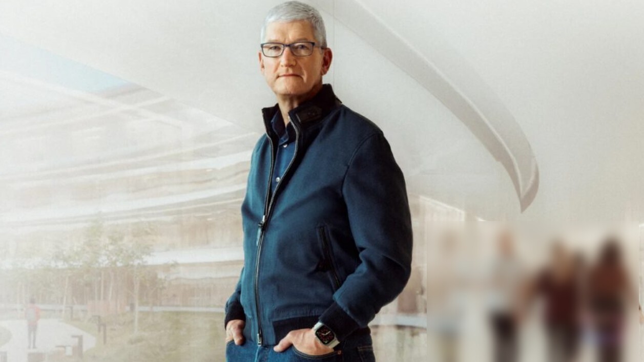 من موقع فون إسلام: يقف رجل ذو شعر رمادي ونظارة طبية في الداخل، يشبه تيم كوك ويرتدي سترة زرقاء بسحاب وبنطالاً داكن اللون، ويضع إحدى يديه في جيبه.