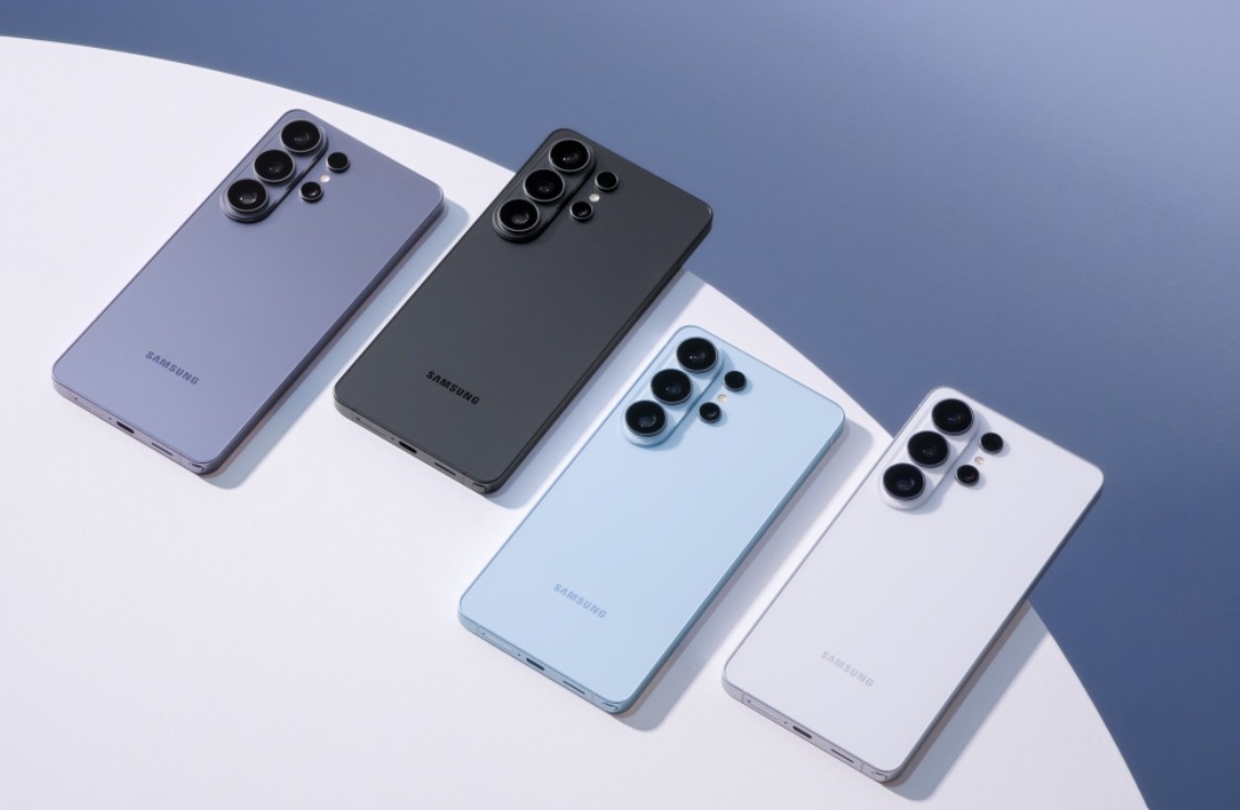 من موقع فون إسلام: تم عرض أربعة هواتف ذكية من سامسونج بألوان مختلفة - الأرجواني والأسود والأزرق والأبيض - على سطح فاتح ومظلم، تظهر كاميراتها الخلفية. تم الكشف عن هذه النماذج مؤخراً في مؤتمر سامسونج.