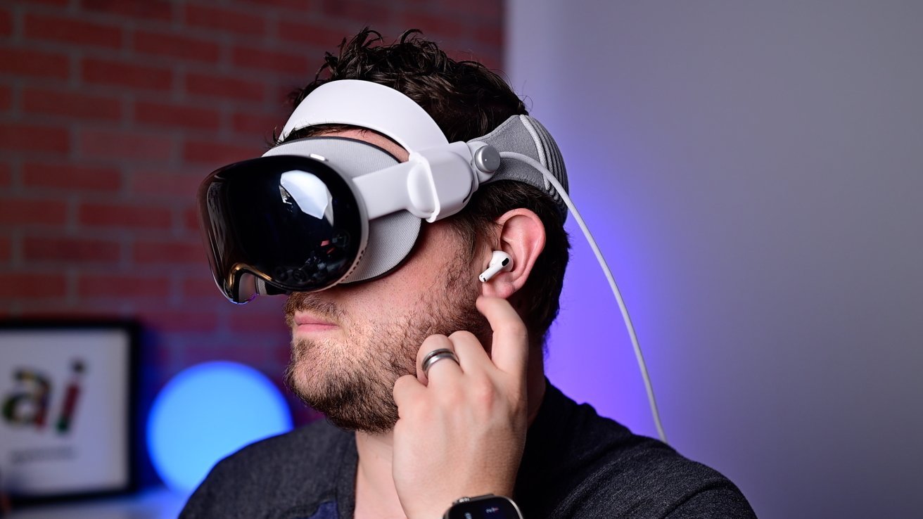 من موقع فون إسلام: شخص يرتدي سماعة رأس الواقع الافتراضي وسماعة أذن لاسلكية، ويضبط سماعة الأذن أثناء ترقب الميزة المنتظرة في أحدث التقنيات.