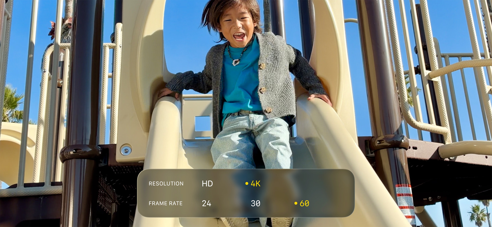 من موقع فون إسلام: طفل ينزلق على منزلق في الملعب في يوم مشمس، تم تصويره بتفاصيل مذهلة - نص تراكبي يعرض نصًا عالي الدقة و4K ومعدلات إطارات: 24, 30, 60. تم التصوير على آي-فون 17e مع شريحة A19 القوية لـ سعر تناسي 17e.