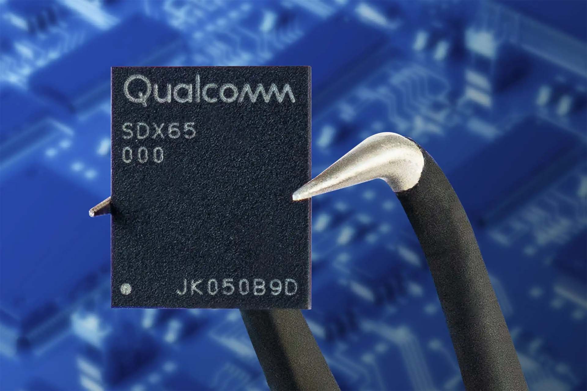 من موقع فون إسلام: رقاقة SDX65 من Qualcomm ممسوكة بملاقط على خلفية لوحة دوائر زرقاء غير واضحة، تذكرنا بالدقة الموجودة في أجهزة M5 وتقنيات أبل سيلي.
