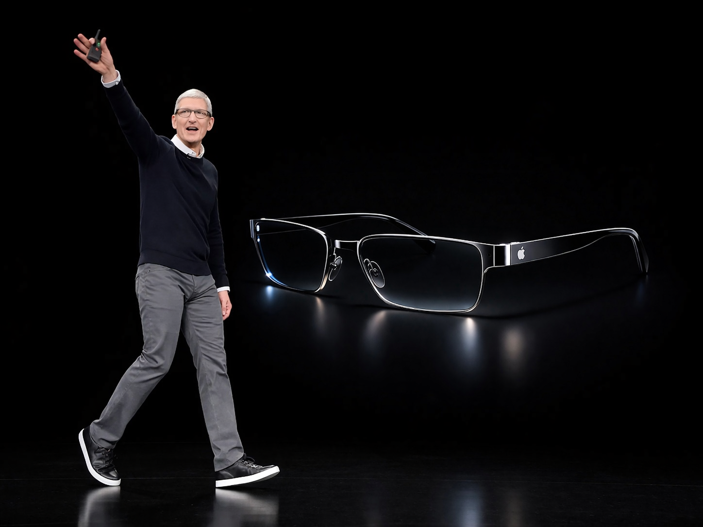 من موقع فون إسلام: شخص يرتدي ملابس غير رسمية يومئ على خشبة المسرح بجانب عرض رقمي كبير لنظارات نظارات آبل الذكية المستقبلية التي تحمل شعار أبل الشهير على خلفية سوداء أنيقة.