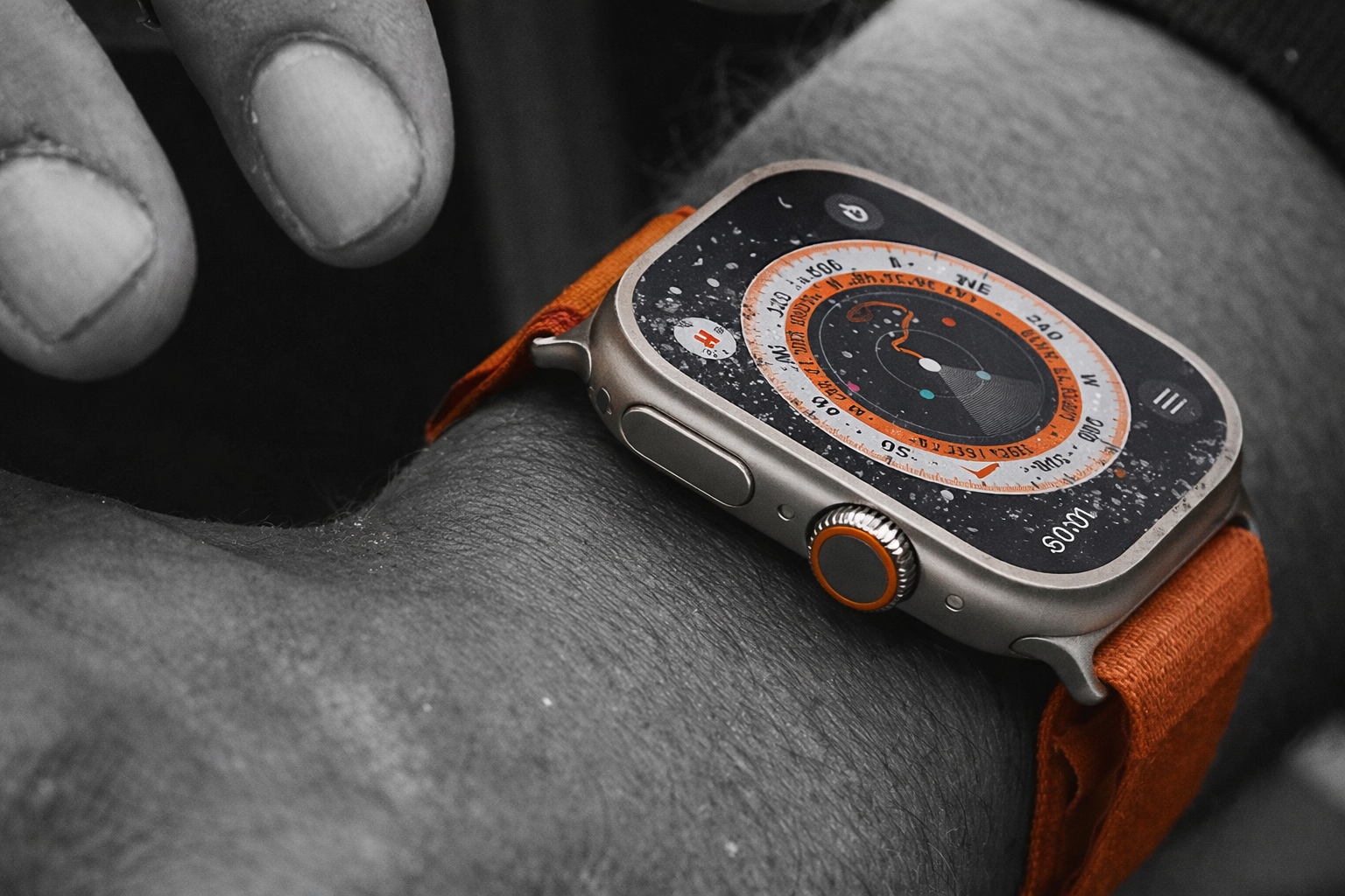 من موقع فون إسلام: لقطة مقربة لساعة آبل الترا الترا 4 مع سوار برتقالي يعرض واجهة بوصلة على معصم الشخص.