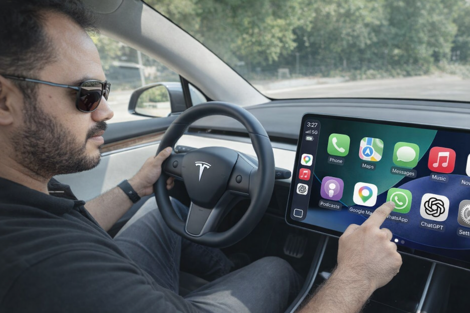 من موقع فون إسلام: يجلس شخص في سيارة تسلا، ويستخدم شاشة العرض التي تعمل باللمس التي تعرض أيقونات تطبيقات مختلفة - مثل الخرائط وواتساب وواتساب والدردشة على نظام CarPlay - بينما يمسك بعجلة القيادة.