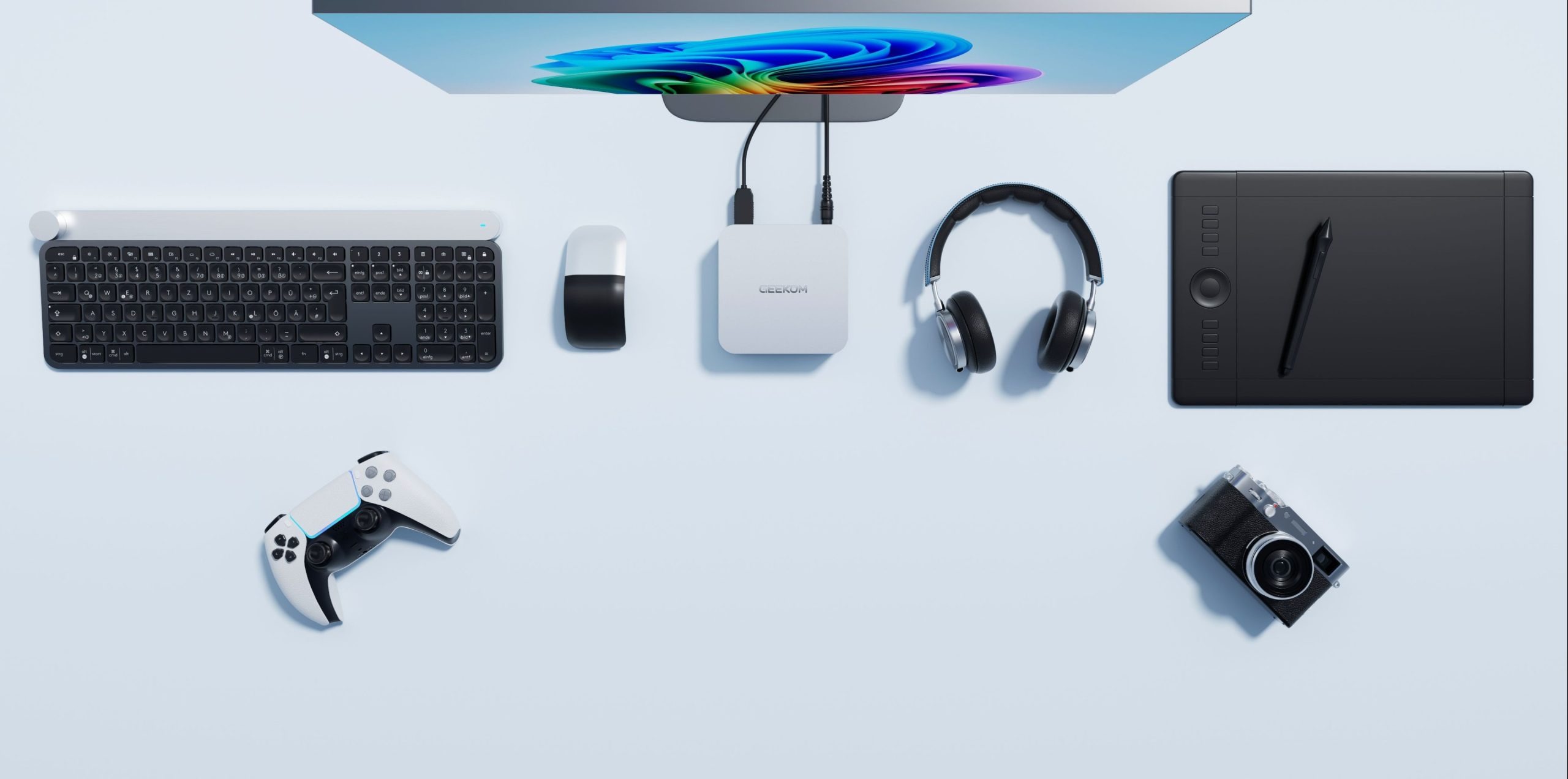 من موقع فون إسلام: إعداد سطح مكتب يضم شاشة، ولوحة مفاتيح، وماوس لاسلكي، وجهاز كمبيوتر صغير من جهاز GEEKOM A6، وسماعات رأس، ولوحة رسم، ووحدة تحكم في الألعاب، وكاميرا مرتبة بشكل أنيق على سطح خفيف.