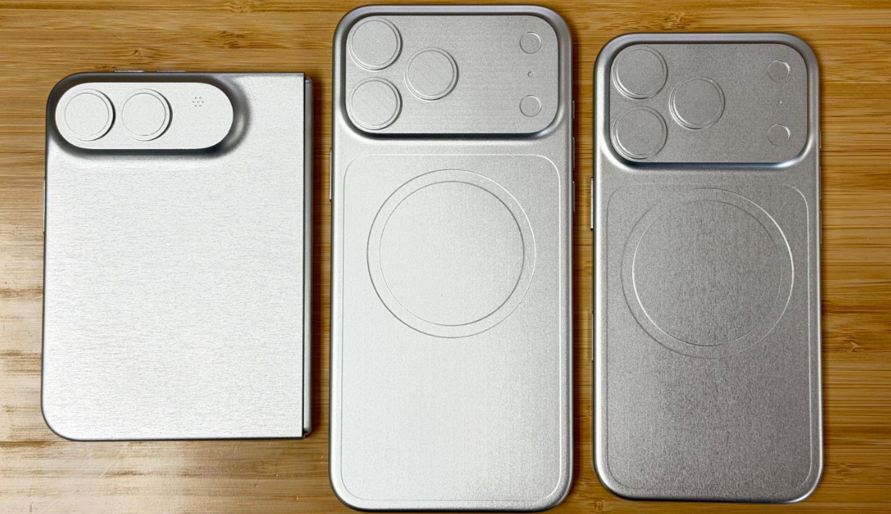 من موقع فون إسلام: ثلاثة نماذج معدنية آي-فون ألترا للهواتف الذكية مزودة بوحدات كاميرا مرتفعة موضوعة جنباً إلى جنب على سطح خشبي.