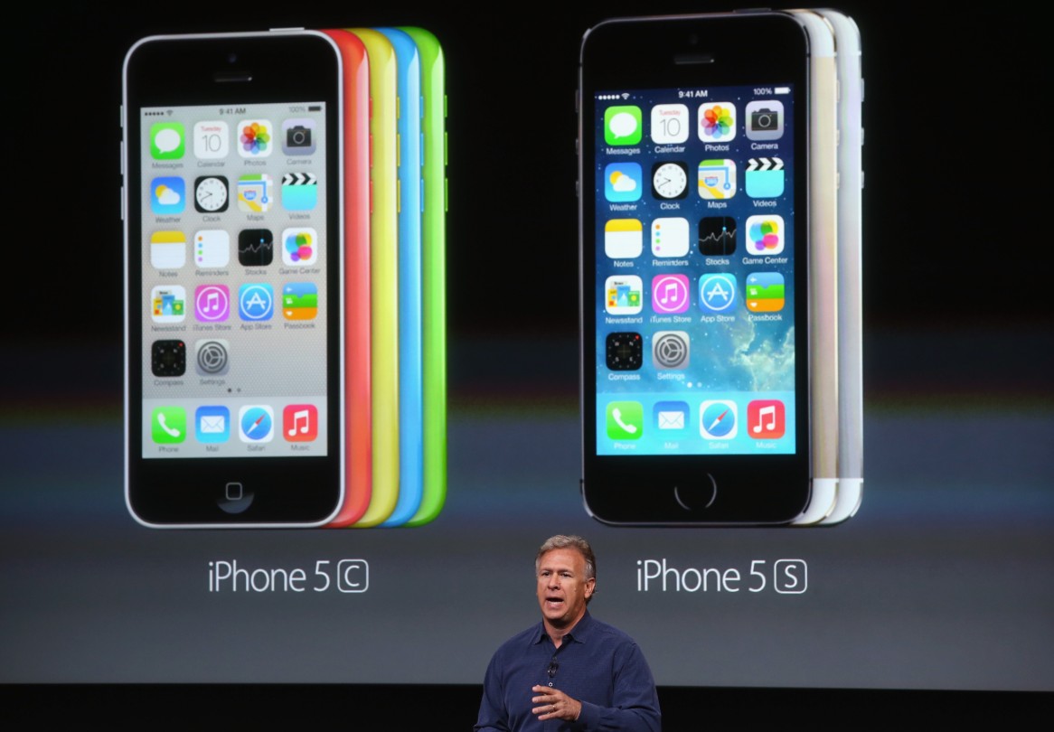 من موقع فون إسلام: يقف مقدم العرض أمام شاشة تعرض صورًا لـ آبل-فون 5C البلاستيكي في ألوان متعددة وآي-فون 5S ألوان ثلاثة.