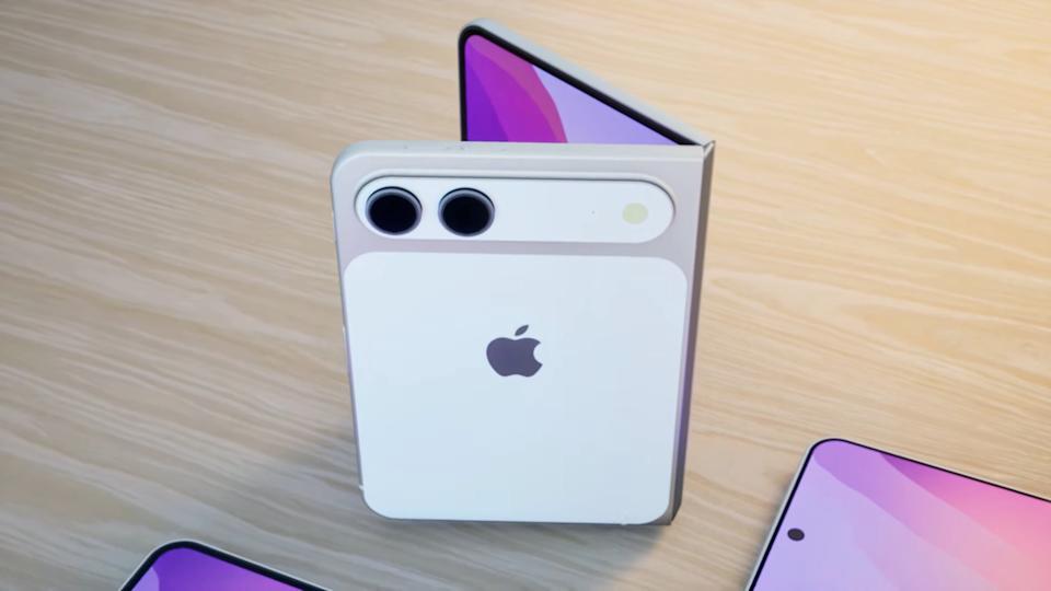 من موقع فون إسلام: يُعرض جهاز آيفون نموذجي قابل للطي يتميز بكاميرا خلفية مزدوجة وشعار آبل وهو مطوي جزئياً على سطح خشبي خفيف إلى جانب هاتفين ذكيين مسطحين، مما يشير إلى تصميم مستوحى من ألوان آي برو 18 النابضة بالحياة.