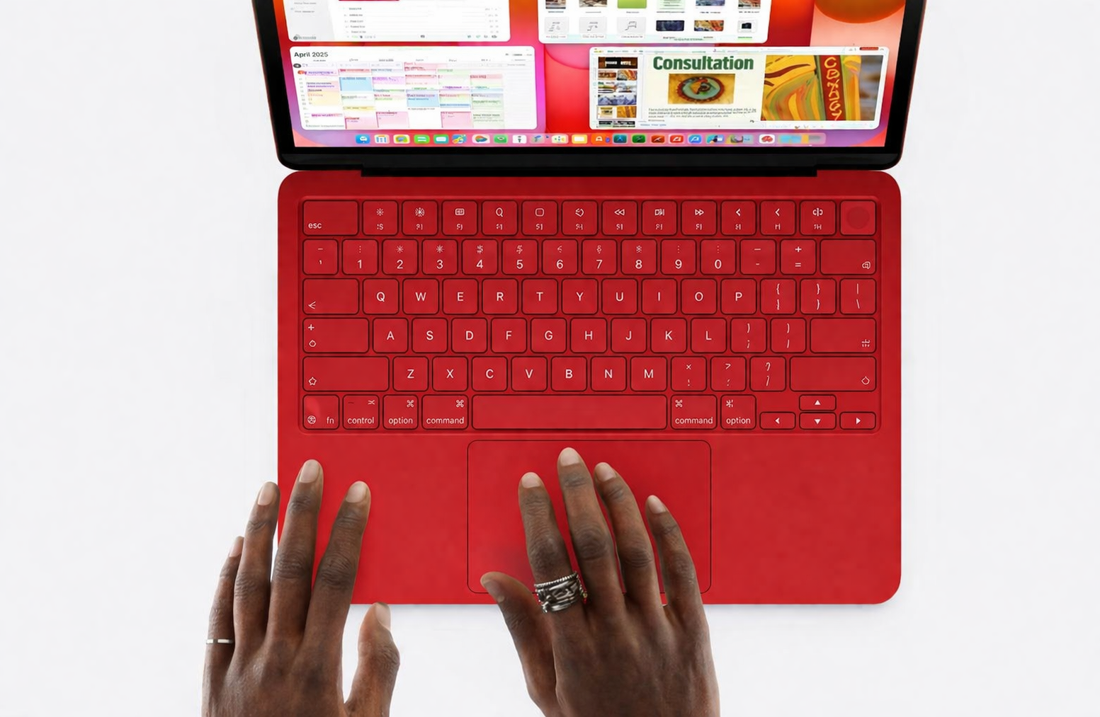 من موقع فون إسلام: شخص يكتب على لوحة مفاتيح ماك بوك نيو حمراء زاهية اللون مع شاشة ملونة تعرض العديد من النوافذ والتطبيقات المفتوحة.