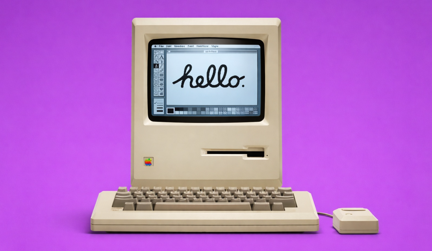 من موقع فون إسلام: كمبيوتر آبل ماكنتوش قديم مع لوحة مفاتيح وفأرة على خلفية أرجوانية. تعرض الشاشة كلمة "مرحباً" بخط اليد.