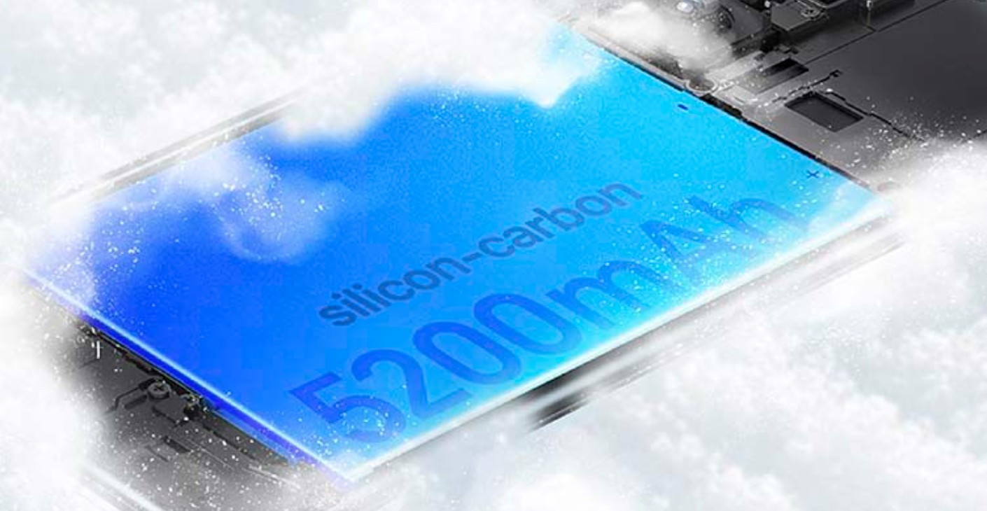 من موقع فون إسلام: صورة مقربة لبطارية زرقاء مكتوب عليها "سيليكون-كربون 5200 مللي أمبير في الساعة"، وهي إحدى البطاريات السيليكونية السيليكونية المتطورة كربون محاطة جزئياً بضباب أو بخار داخل جهاز إلكتروني.