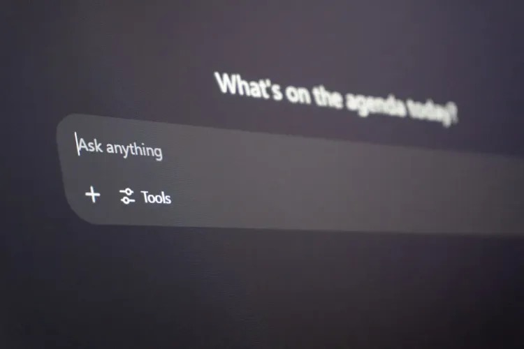 من موقع فون إسلام: شاشة كمبيوتر تعرض شريط بحث مع المطالبة "اسأل أي شيء"، وخيار بعنوان "أدوات"، وتلميحات لأحدث تحديث سيري iOS 27 تظهر أسفل عنوان غير واضح.