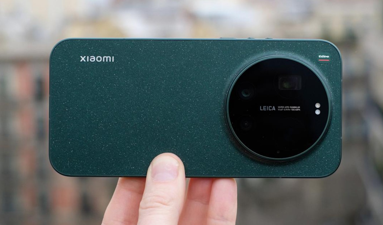 من موقع فون إسلام: يد تحمل هاتفًا ذكيًا أخضر داكن اللون من شاومي، وغالبًا ما يطلق عليه اسم "الآي-فون الأندرويد"، ويتميز بوحدة كاميرا كبيرة مستديرة تحمل علامة لايكا في الخلف.