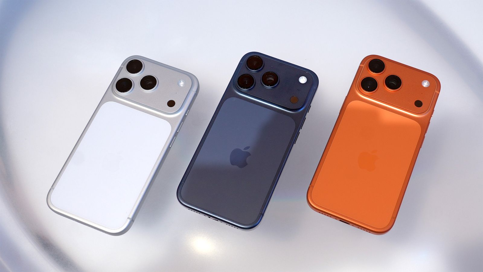 من موقع فون إسلام: يتم عرض ثلاثة هواتف آيفون من Apple باللون الأبيض والأزرق والبرتقالي جنباً إلى جنب، حيث تعرض وحدات الكاميرا الخاصة بها على سطح أملس وخفيف - إضافة مثالية إلى أخبار الأسبوع في مجال التكنولوجيا.