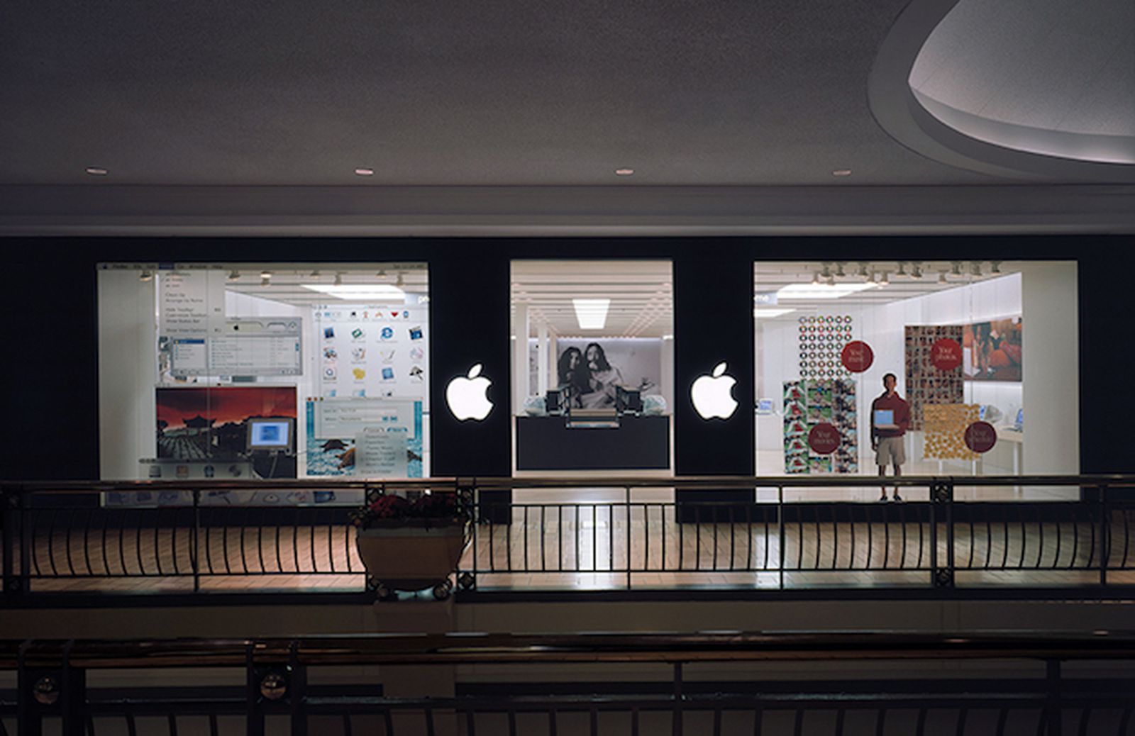 من موقع فون إسلام: واجهة متجر بها ثلاث نوافذ عرض تحمل شعارات شركة Apple، وإعدادات كمبيوتر قديمة، وشخص يقف بالداخل ممسكاً بجهاز كمبيوتر محمول - وهي واجهة مثالية لـ.