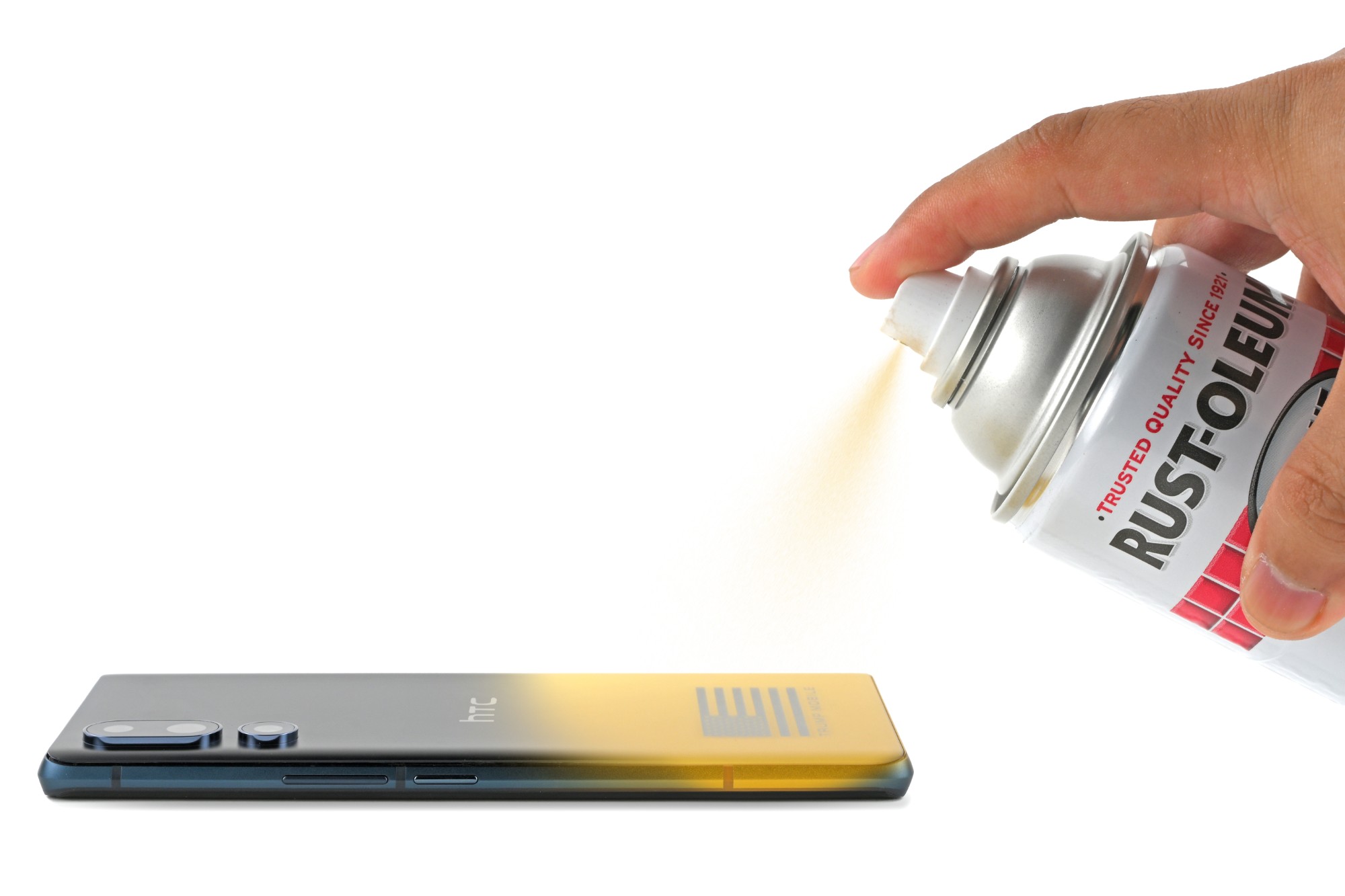 From Phonegram website: A hand spraying yellow paint from a 'Rust-Oleum' can onto the back of a black 'Trump T1' smartphone.