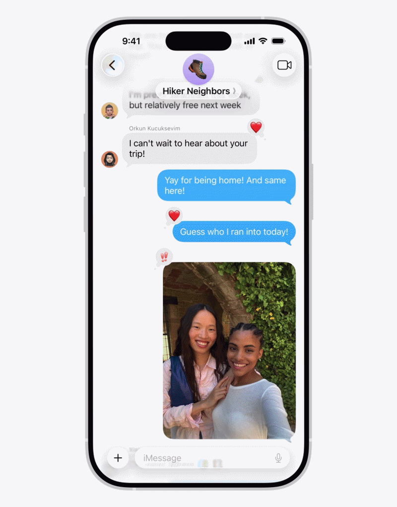من موقع فون إسلام: شاشة آيفون تُظهر محادثة جماعية عبر iMessage تضم صورتين لامرأتين تبتسمان وتقفان معًا في إحدى الصور. وتظهر في المحادثة ردود فعل على شكل قلب وعلامة السلام، مما يسلط الضوء على بعض ميزات iMessage الخفية للتفاعل مع الصور والرسائل.
