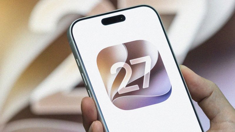 From Phonegram website: A hand holding a smartphone displaying an app icon with the number 27 in white on a beige and purple swirling background, to highlight some of the iOS 27 features.