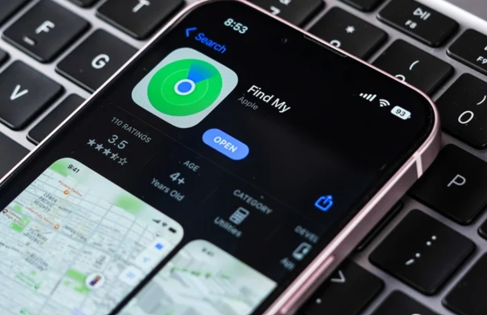 من موقع فون إسلام: يُظهر هاتف ذكي صفحة تطبيق «Find My» في متجر التطبيقات، مع التركيز على «حماية الآي-فون»، وهو موضوع على لوحة مفاتيح كمبيوتر سوداء.