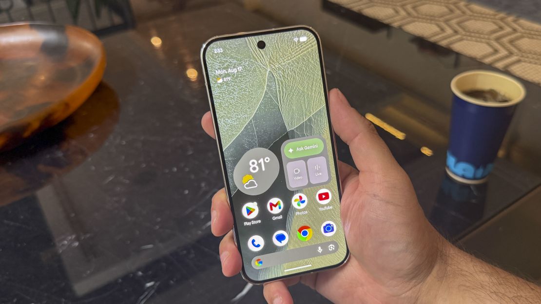From Phonegram: A hand holding a smartphone with a cracked screen, displaying various app icons and a weather widget showing 81 degrees Fahrenheit — a daily scene that might lead you to compare the iPhone 17 Pro and Pixel 11 Pro in preparation for your next phone upgrade.
