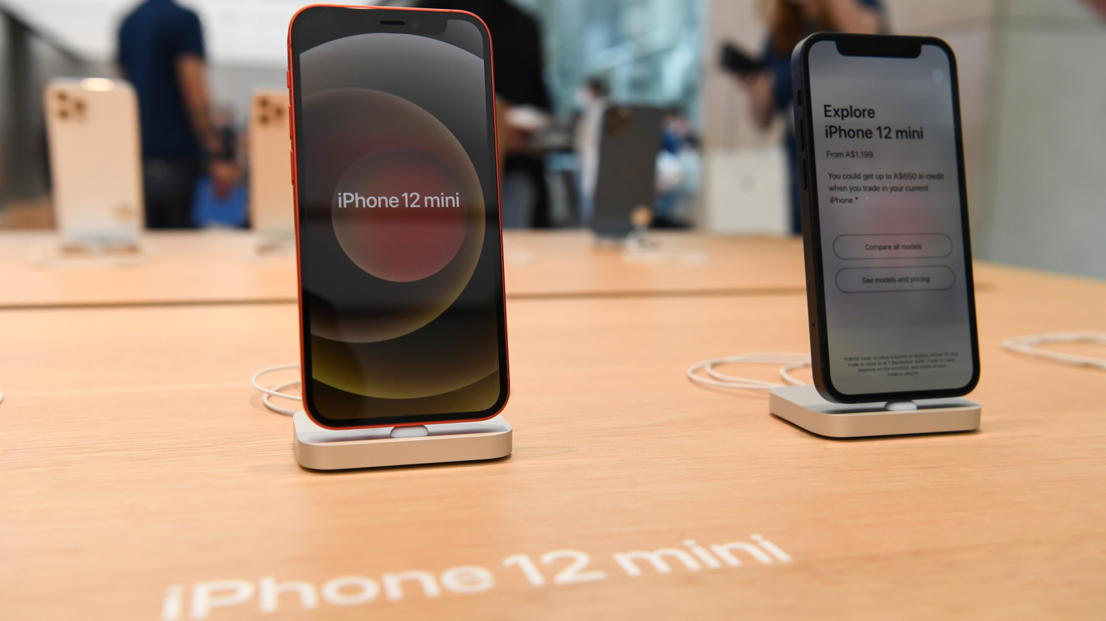 من موقع فون إسلام: يُعرض هاتفان ذكيان من طراز iPhone 12 mini على طاولة خشبية؛ يعرض أحدهما الشاشة الرئيسية، بينما يعرض الآخر معلومات عن الجهاز.