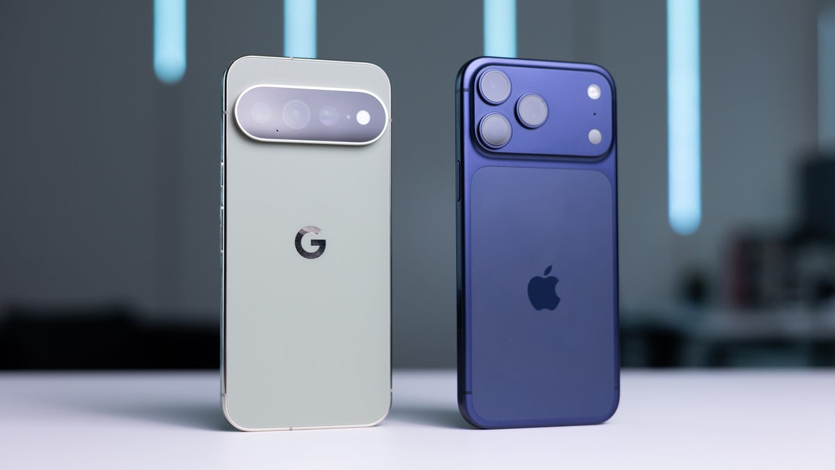From Phonegram: A Google Pixel smartphone and an Apple iPhone are shown standing vertically side-by-side on a white surface in a blurry indoor scene, perfectly capturing the essence of an iPhone 17 Pro and Pixel 11 Pro comparison.