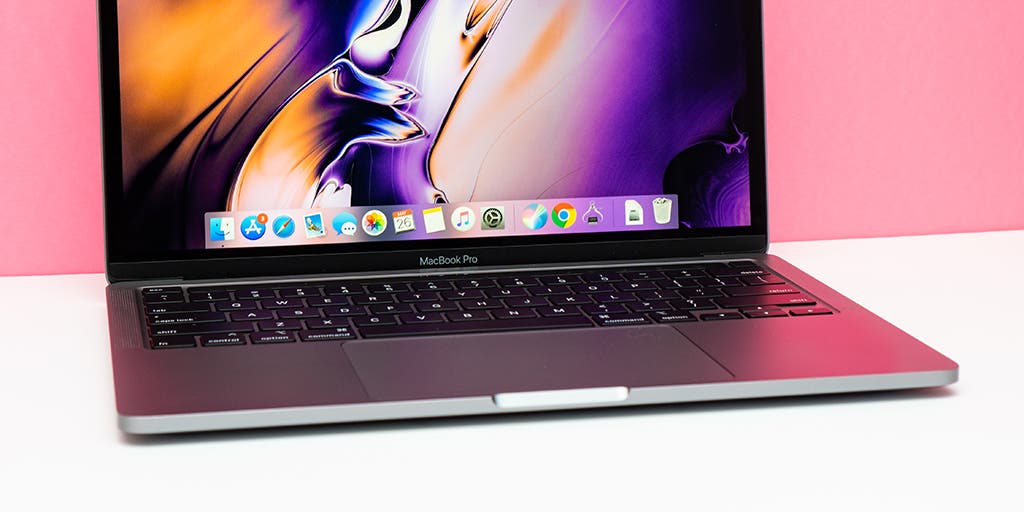 من موقع فون إسلام: يوجد جهاز كمبيوتر محمول من طراز MacBook Pro على سطح أبيض وشاشته مضاءة، حيث تعرض سطح المكتب وقائمة التطبيقات المثبتة على خلفية وردية، وهو مشهد مثالي لمتابعة «ملخص تقني» أو البقاء على اطلاع بـ«أخبار التقنية».