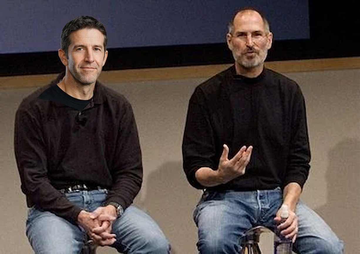 From the Phonegram website: Two men sit on chairs, both wearing long-sleeved black shirts and blue jeans, speaking on stage in front of a simple background. One of them is John Ternus, known for his significant influence in the tech industry.
