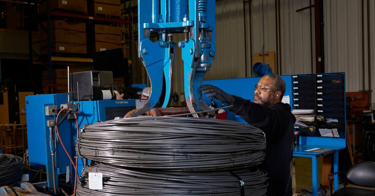 From the Phonegram website: A factory worker uses a blue hydraulic crane to move a large coil of steel wire, in one of this week's top stories.