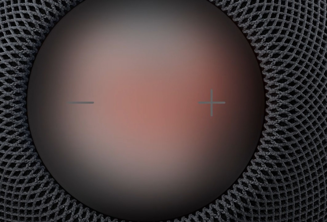 من موقع فون إسلام: منظر علوي لمكبر الصوت الذكي «HomePod mini 2» المزود بسطح لمس دائري عليه علامتا «+» و«-».