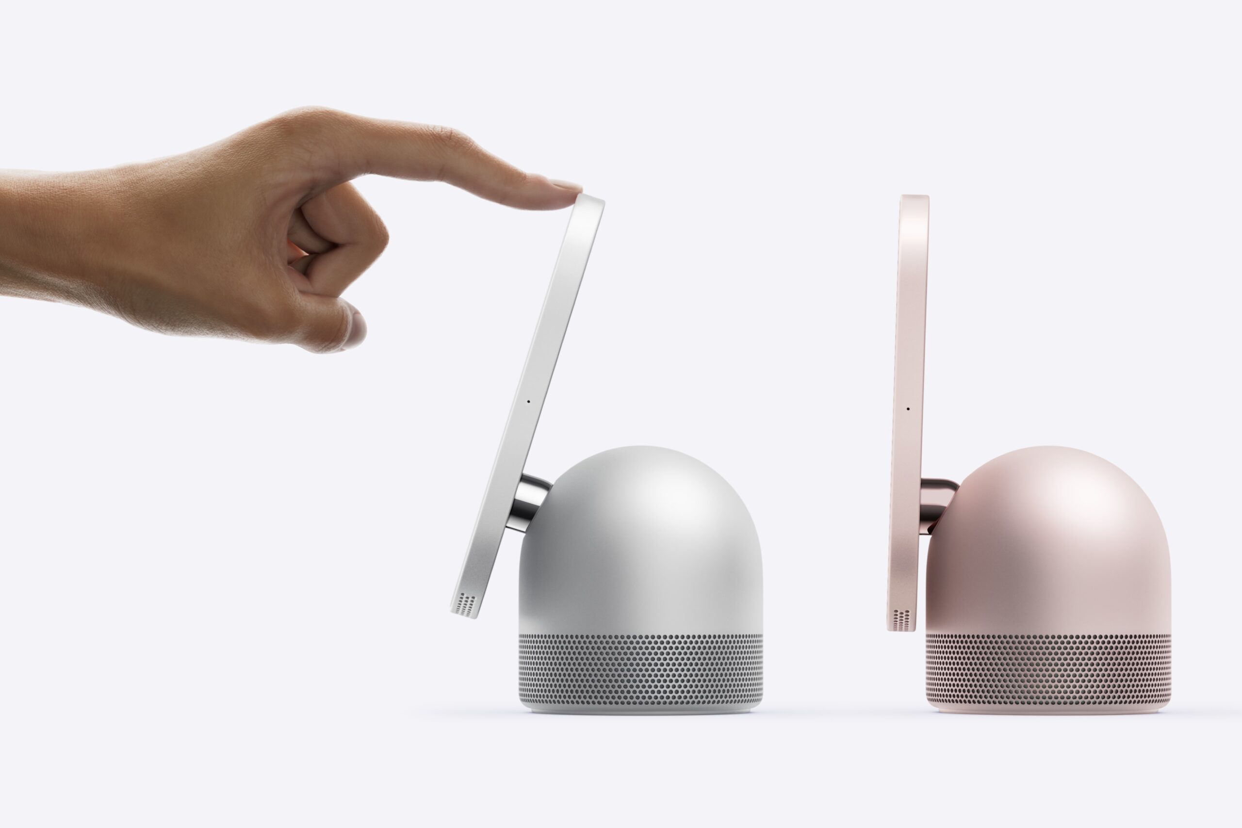 من موقع فون إسلام: تلمس يد الجزء العلوي من مكبر صوت ذكي من طراز «Apple Home View» فضي اللون مزود بشاشة عمودية، بجانب مكبر صوت آخر مطابق له بلون الذهب الوردي.